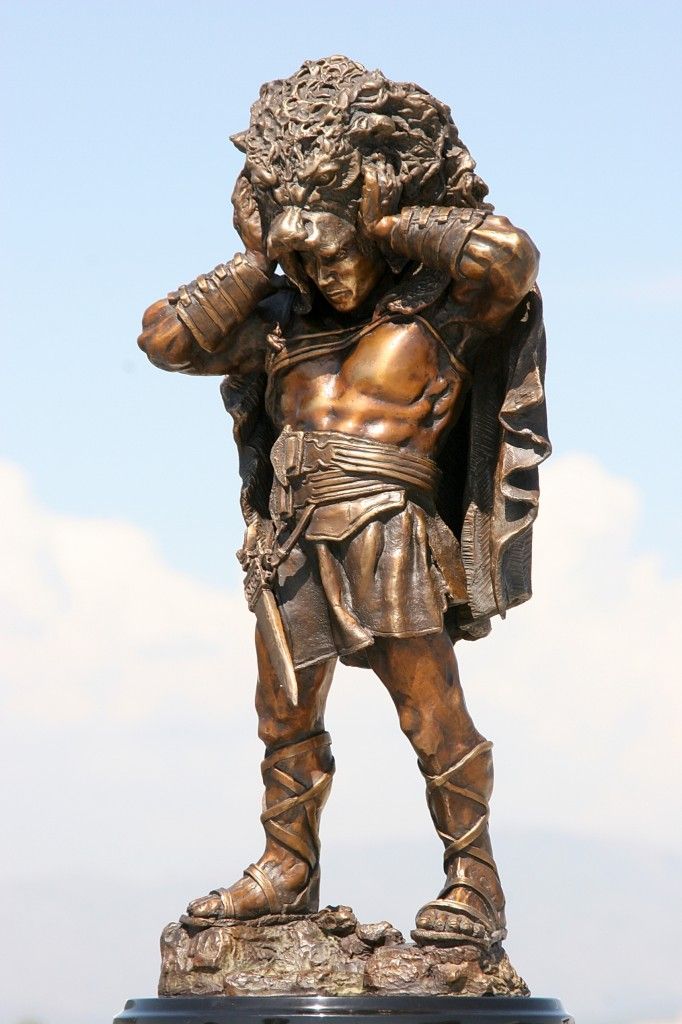 a bronze statue of a man holding his head