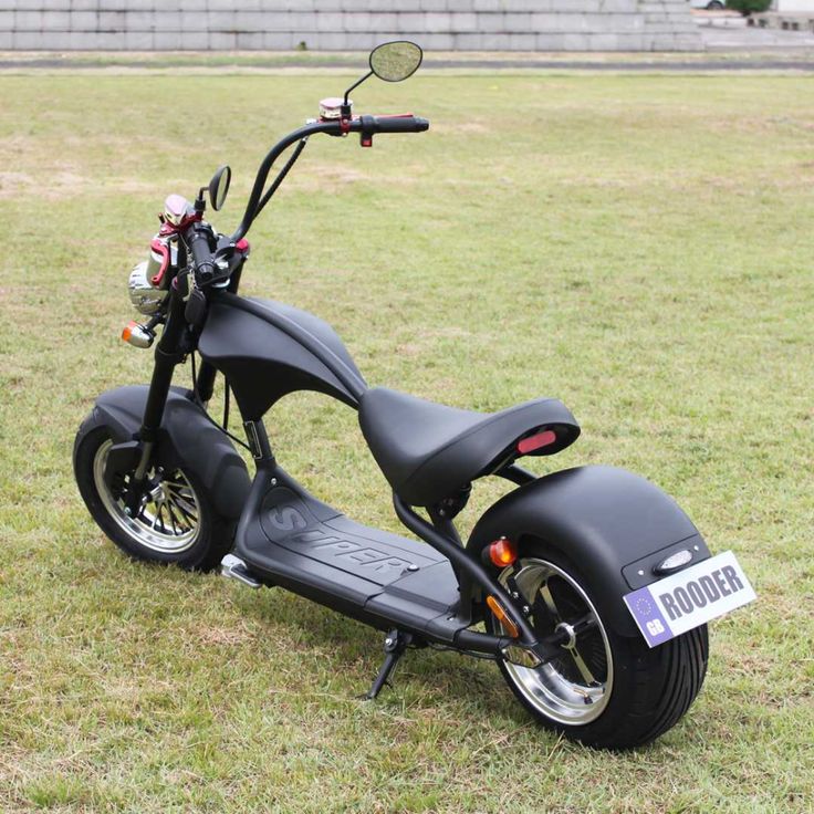 a black scooter parked on top of a lush green field