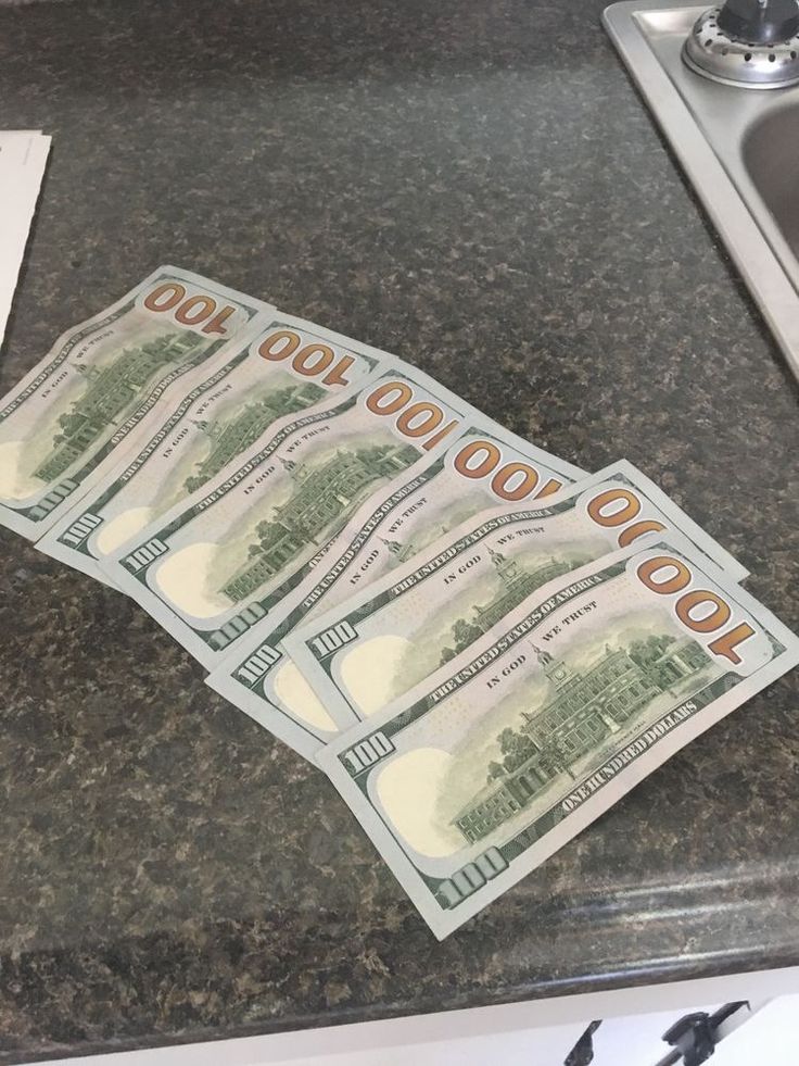 five hundred dollar bills sitting on top of a counter next to a sink and faucet