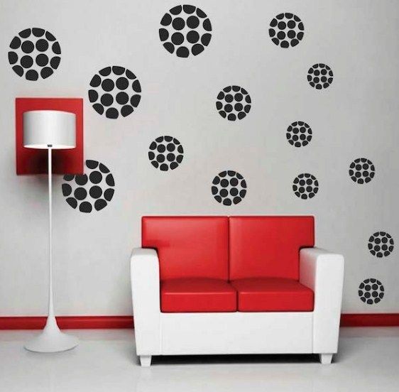 a red couch sitting in front of a wall with black and white circles on it