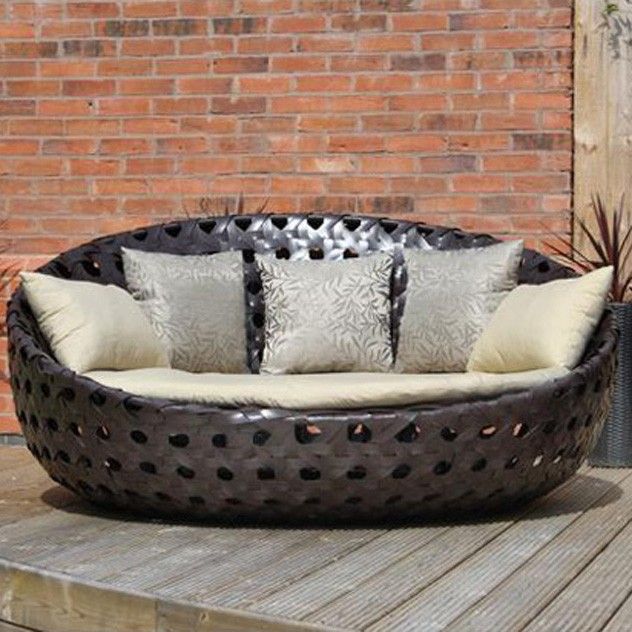 a couch sitting on top of a wooden deck next to a brick wall and potted plants