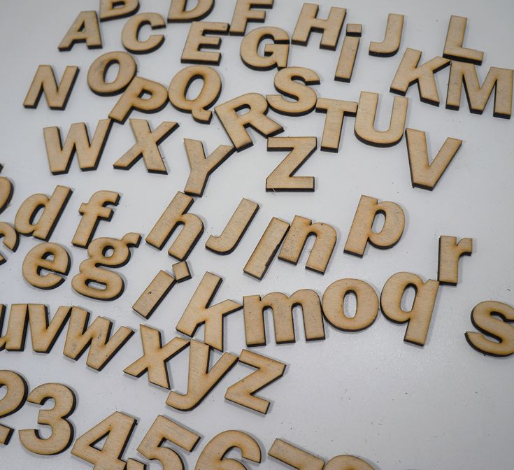 wooden letters and numbers laid out on top of a white surface with one letter missing