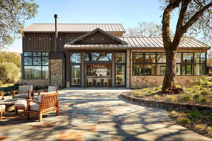 an outdoor patio with chairs and tables in front of a large glass doored building