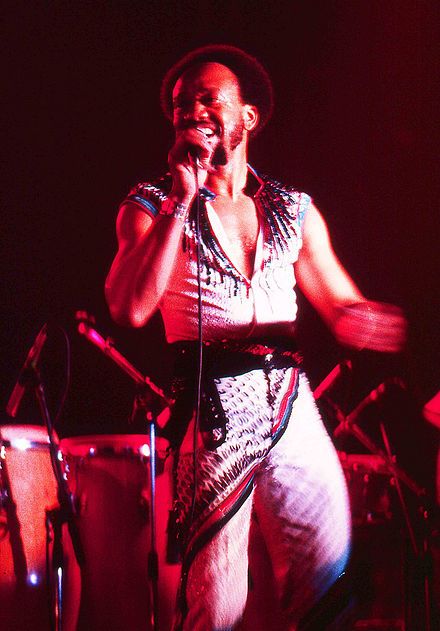 a man standing in front of a microphone on top of a stage next to drums