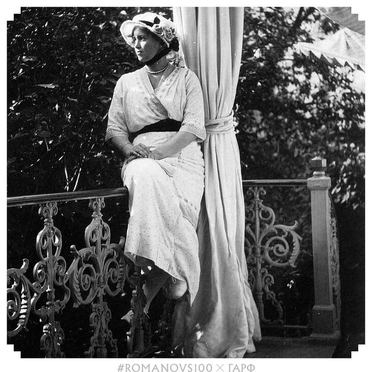 an old black and white photo of a woman sitting on a balcony