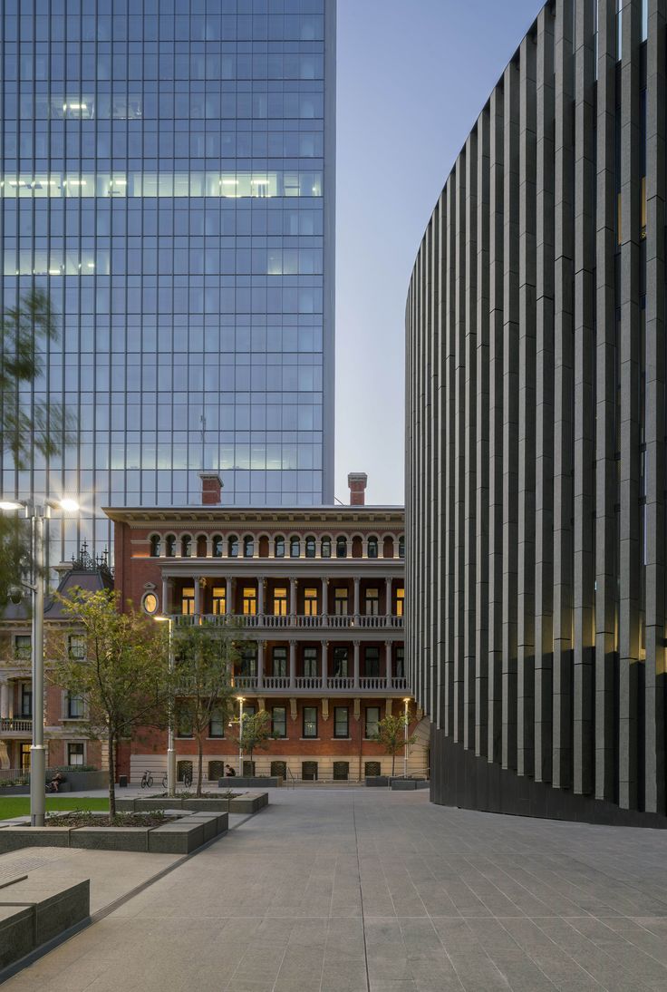 an empty courtyard in front of two tall buildings with glass windows on each side and one large building at the far end