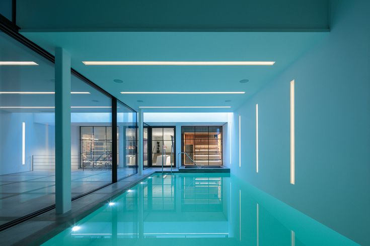 an indoor swimming pool with glass walls and doors