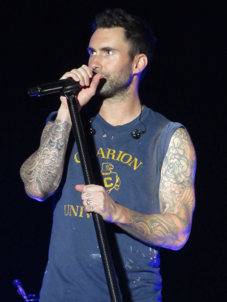 a man with tattoos on his arm holding a microphone