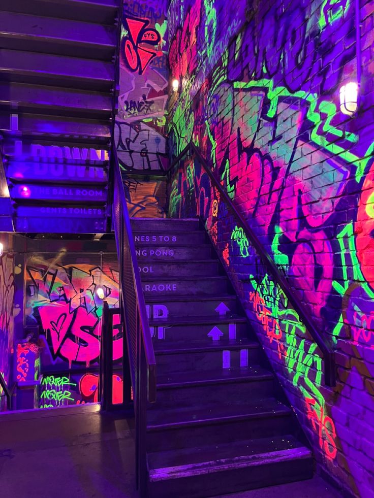 the stairs are covered in graffiti and lit by colorful lights