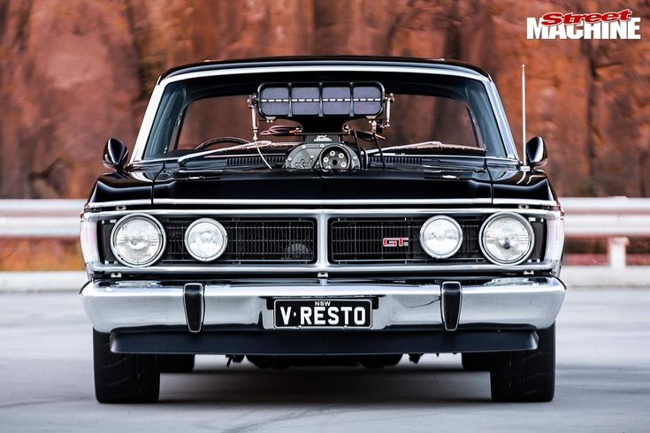 the front end of a black and silver car with an engine on it's hood