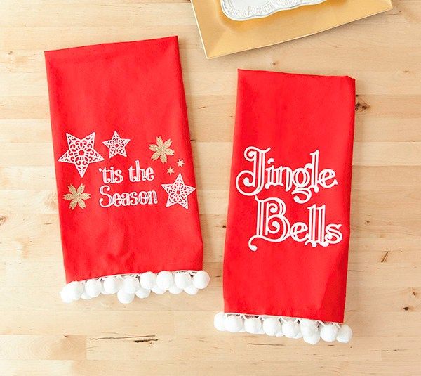 two red towels with white pom - poms on top of a wooden table