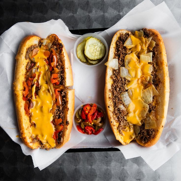 two chili cheese dogs with pickles on the side