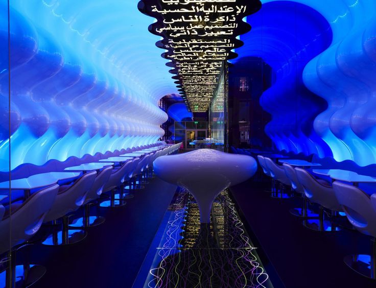 the interior of a restaurant with blue lights and white chairs on either side of it