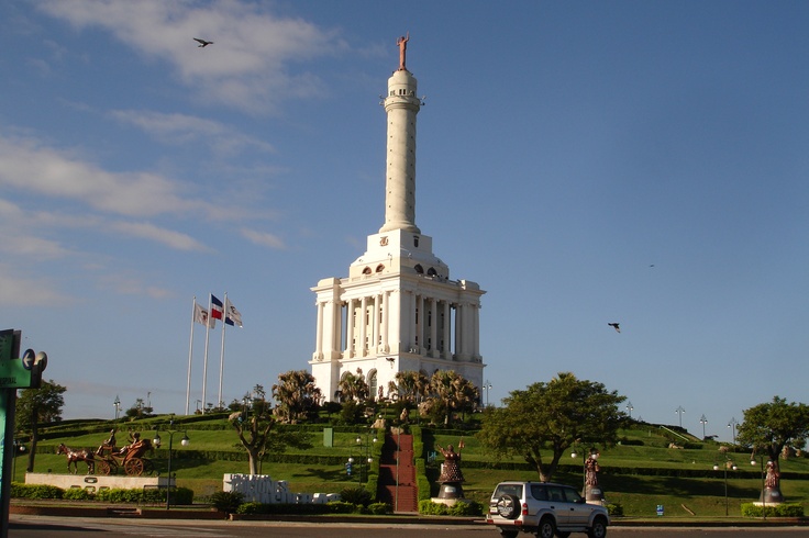 a tall white building with a flag on it's top and trees in the foreground