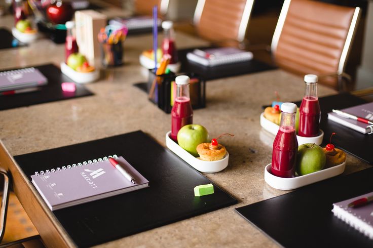 the table is set up for lunch with fruit and juices on it, along with notepads