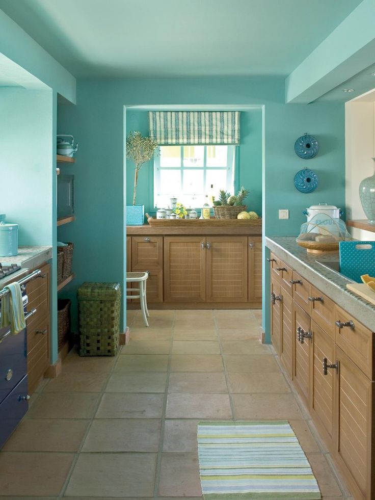 a kitchen with blue walls and tile flooring in the center, along with wooden cabinets