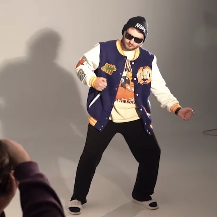 a man wearing sunglasses and a jacket is dancing in front of a person taking a photo