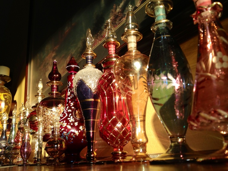 many different colored glass vases are lined up on the shelf next to each other