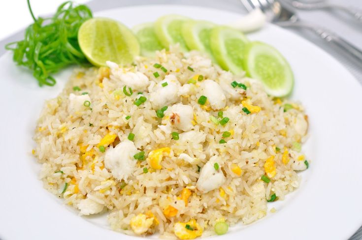 a white plate topped with rice and veggies next to lime wedged slices