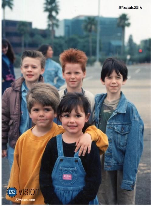 a group of young boys standing next to each other in front of a parking lot