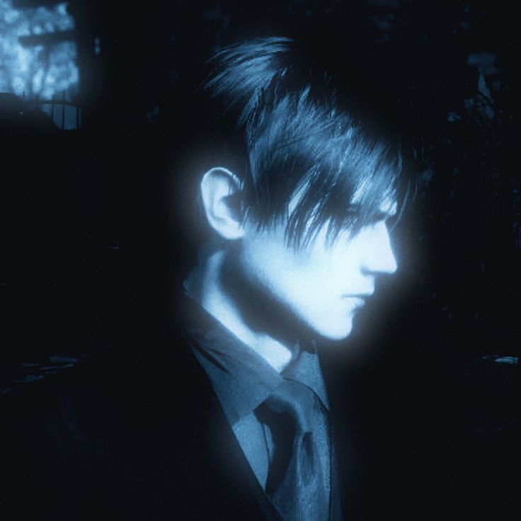 a man with black hair wearing a suit and tie looking at something in the dark