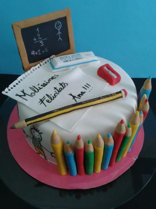 there is a cake with writing and pencils on the top it has a chalkboard in the background