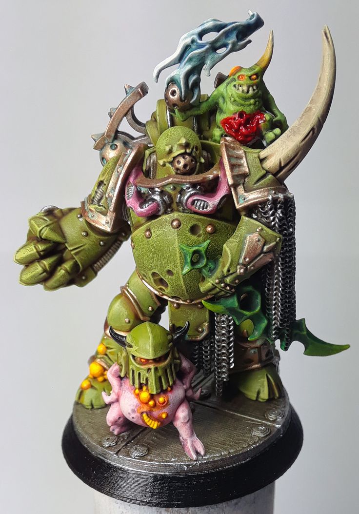 a green and black warhammer with horns on it's head, sitting on top of a table