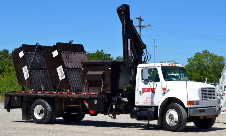 a white dump truck parked in a parking lot next to a crane and power lines