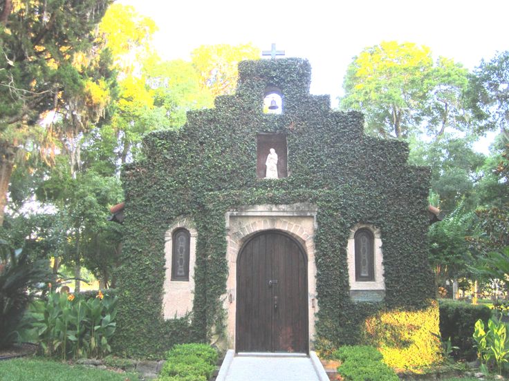 an old church covered in ivy with a clock tower on it's front door