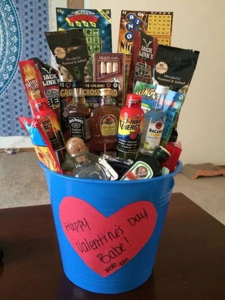 a blue bucket filled with lots of goodies on top of a wooden table next to a wall