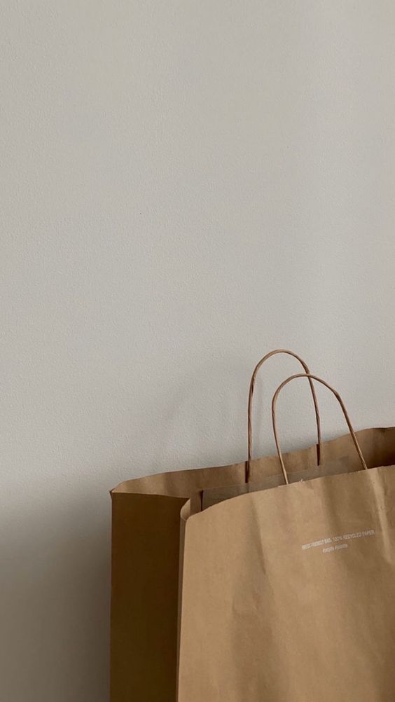 a brown paper bag sitting on top of a wooden table next to a white wall