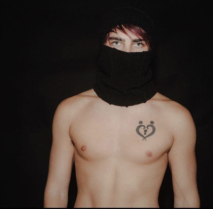 a shirtless man wearing a black bandana with a heart tattoo on his chest