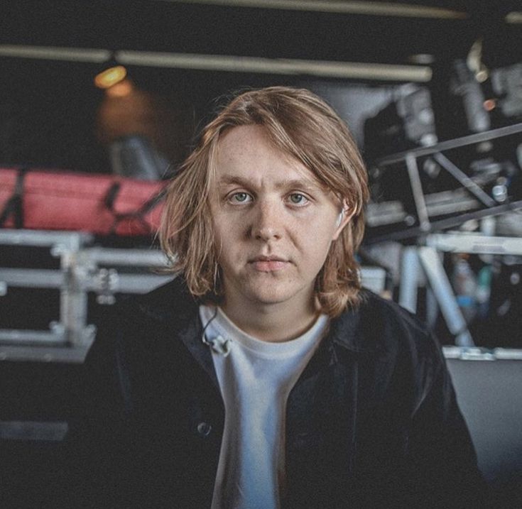 a man with long hair is looking at the camera while wearing headphones in a recording studio