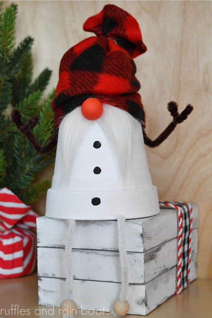 a snowman made out of wood sitting on top of a wooden table next to a christmas tree