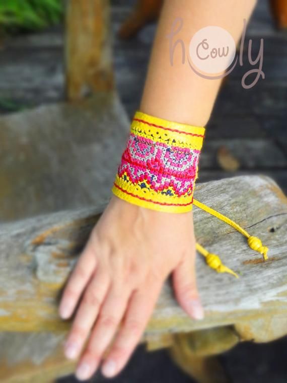 This boho bracelet is 100% handmade from the finest quality yellow leather. It is beautifully designed with vintage Hmong fabric on the front. No sewing machines or assembly lines are in sight. The Hmong tribe are an ethnic hill tribe group which live near me in the mountains in the north of Thailand. The fabric insert used in this bracelet is Hmong vintage tribal tapestry which is beautifully cross stitched. The Hmong people are believed to have been the original inhabitants of the Yellow River Handmade Yellow Cuff Bracelet, Fair Trade Festival Bracelets, Handmade Yellow Cuff Bracelet As Gift, Adjustable Yellow Cuff Bracelet As Gift, Adjustable Yellow Cuff Bracelet For Gift, Handmade Yellow Cuff Bracelet Gift, Yellow Bangle Jewelry For Festival, Handmade Adjustable Cuff Bracelet For Summer, Adjustable Bohemian Yellow Cuff Bracelet