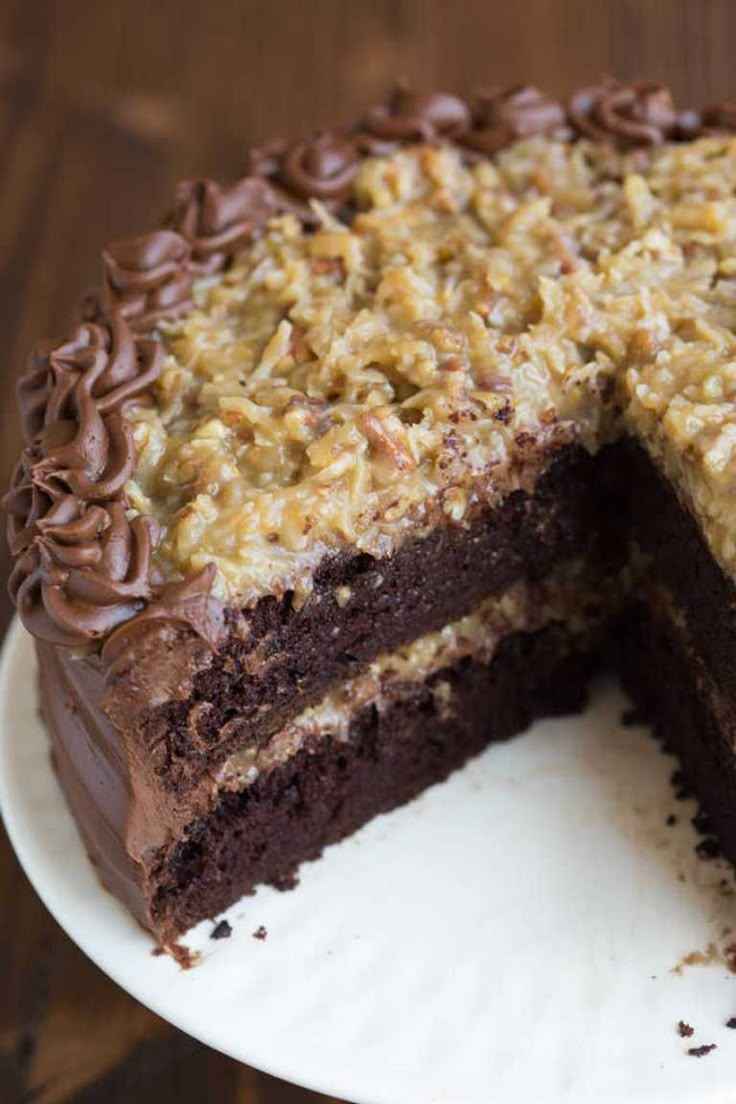 a chocolate cake with walnuts on top and one slice cut out from the cake