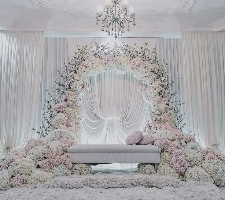 an elegant wedding setup with white flowers and greenery on the stage, chandelier hanging from the ceiling