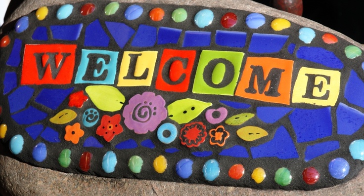 a welcome sign is painted on top of a rock