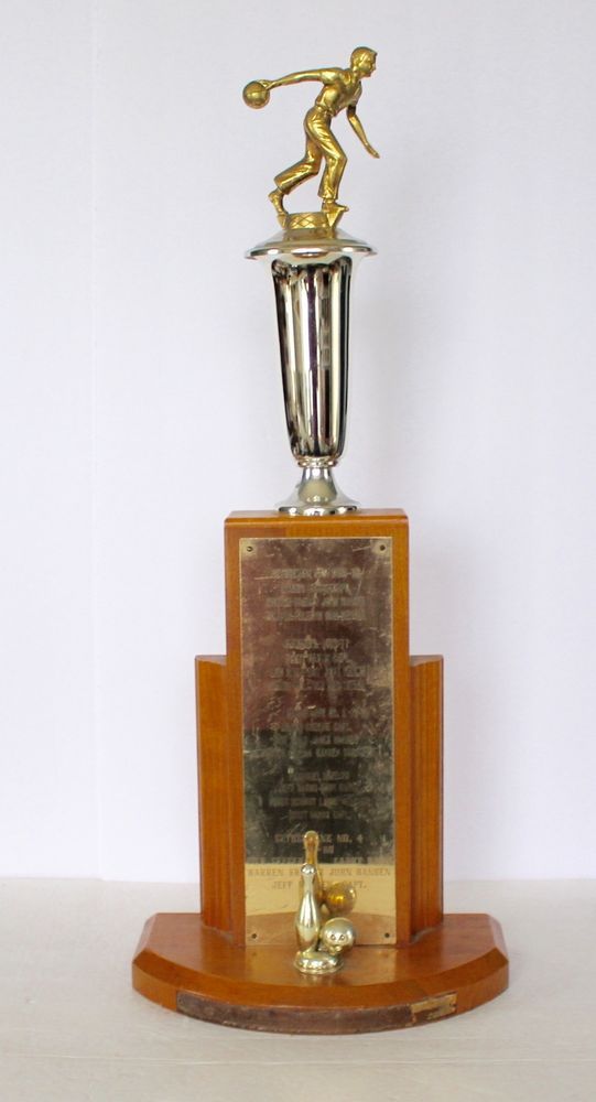 a trophy with a man on it sitting on top of a wooden plaque holder in front of a white wall