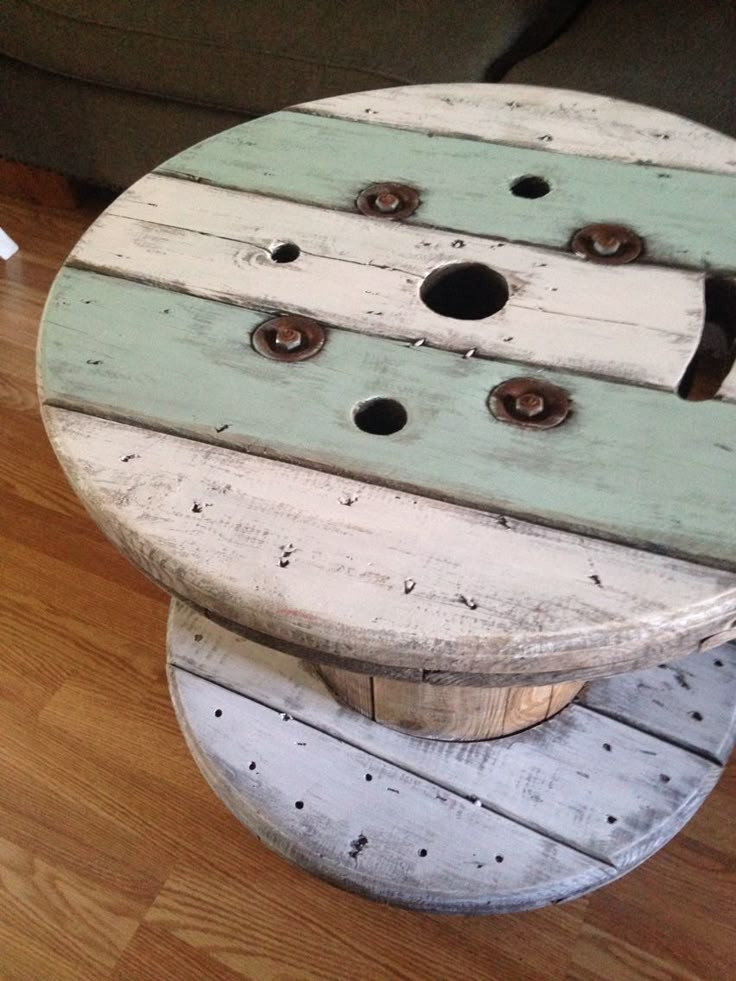 a round wooden table sitting on top of a hard wood floor next to a couch