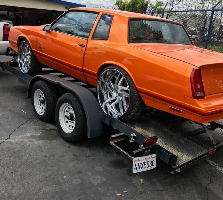 an orange car is being towed by a tow truck