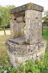 an old stone water fountain sitting in the grass