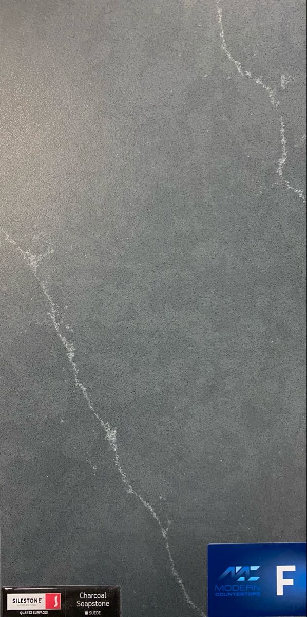 a black marble counter top with white veining on the edges and gray grout