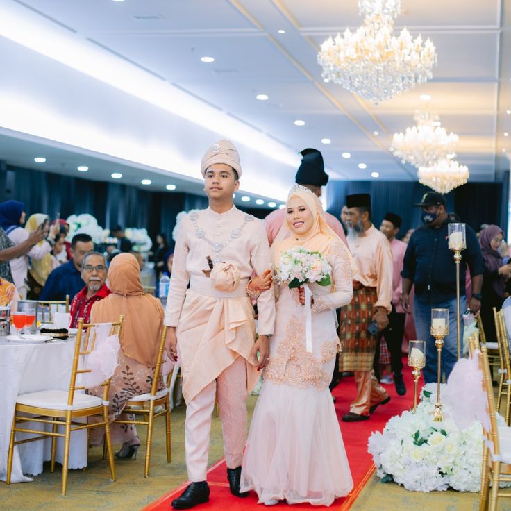 a man and woman walking down a red carpeted aisle with people in the background