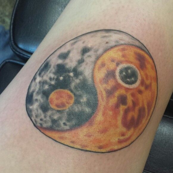 a tattoo on the leg of a person with an orange and black yin yang