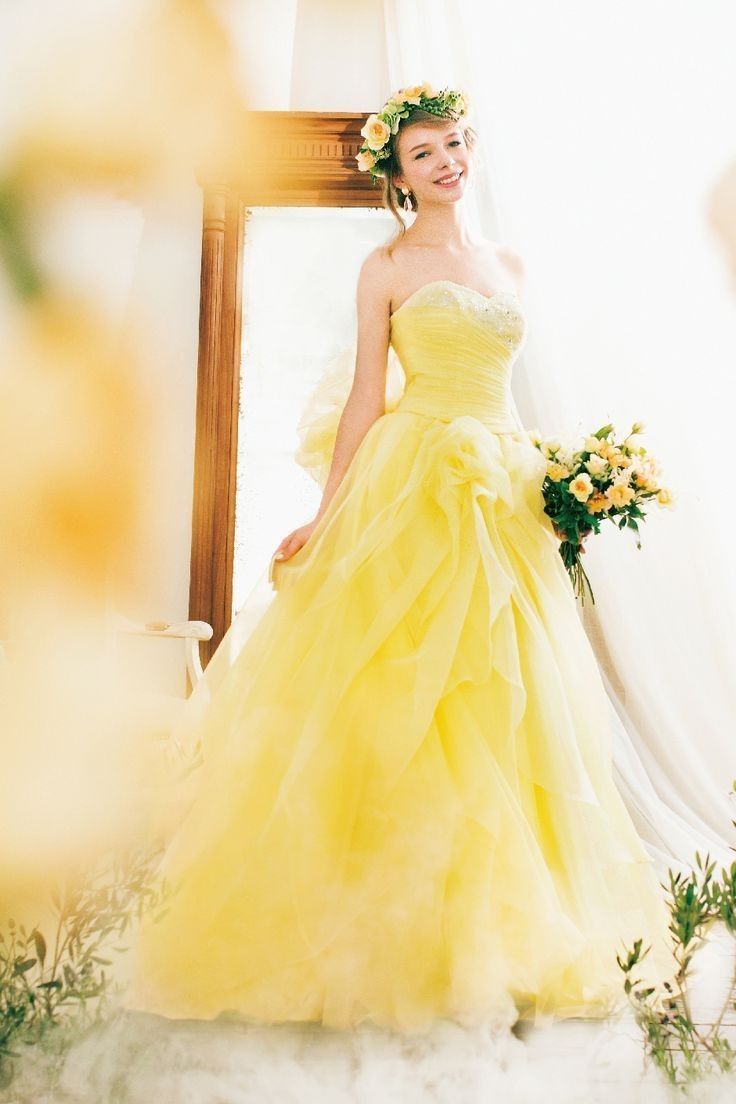 a woman in a yellow dress standing next to a mirror