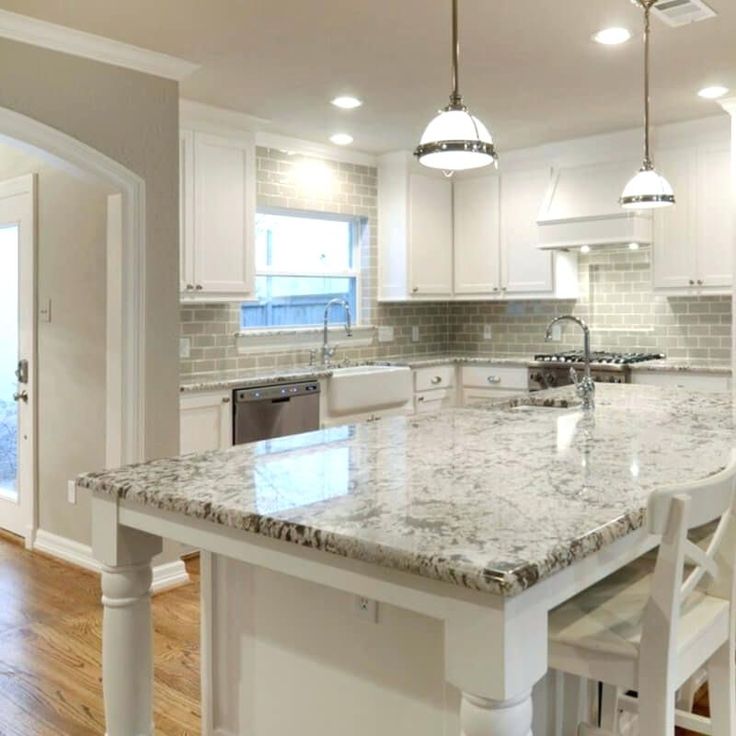 a large kitchen with white cabinets and marble counter tops, along with an island in the middle