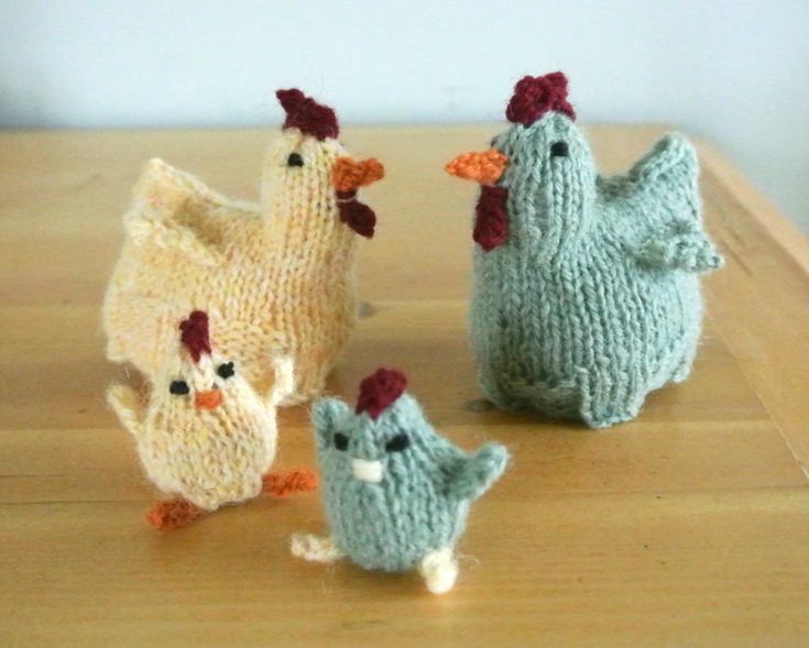 three knitted chickens sitting on top of a wooden table