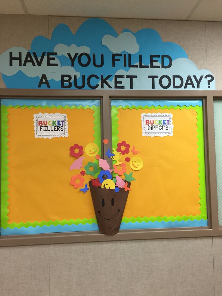 a bulletin board decorated with flowers in front of a door that says have you filled a bucket today?