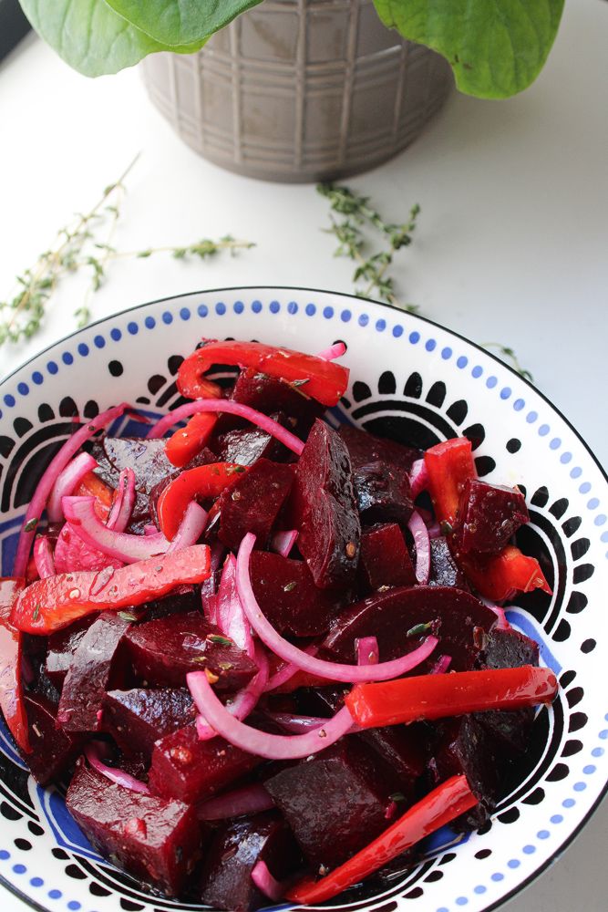 a bowl filled with beets and onions on top of a table next to a potted plant